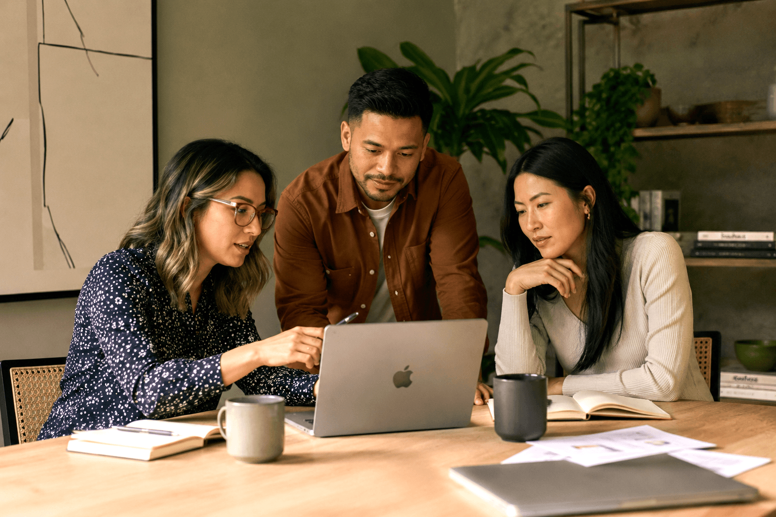 Team of three people at a wood table comparing low code, no code, and vibe coding options on a laptop screen.