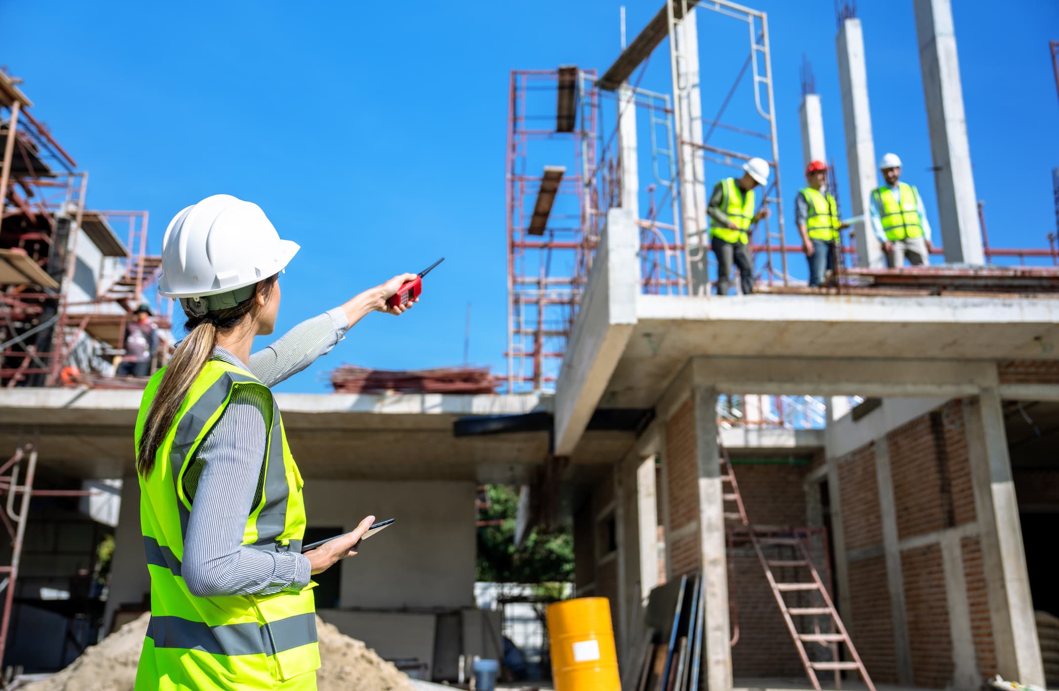 Two groups of people communicate across a construction site