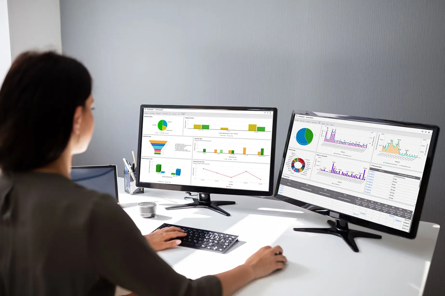 Woman looking at Quickbase product screenshots on two monitors