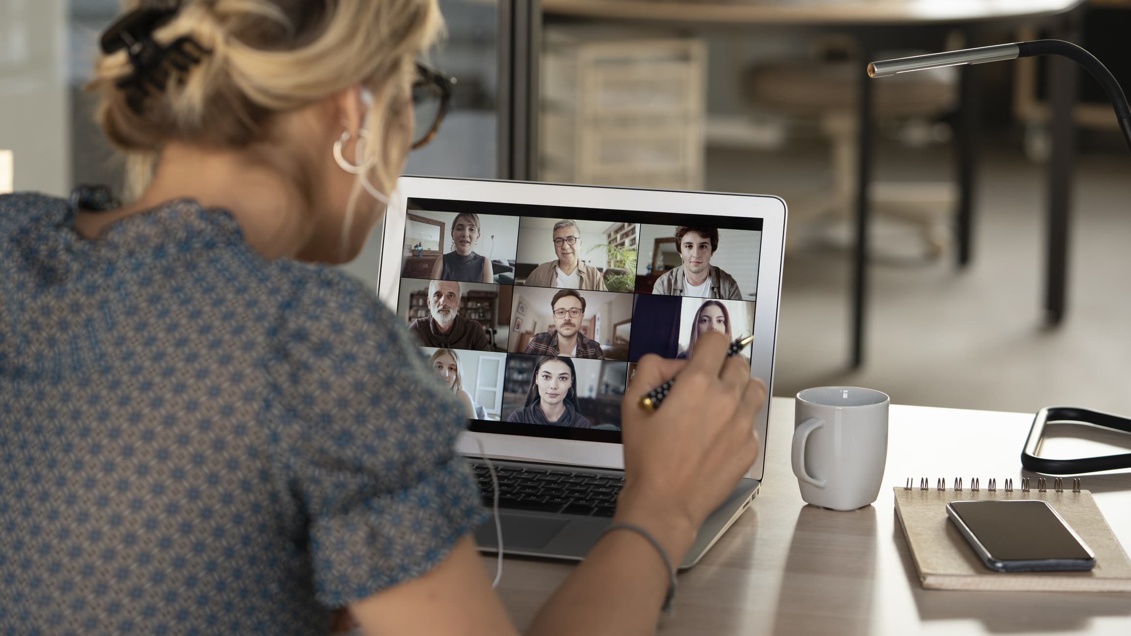 A woman participates in a video call with a group of coworkers