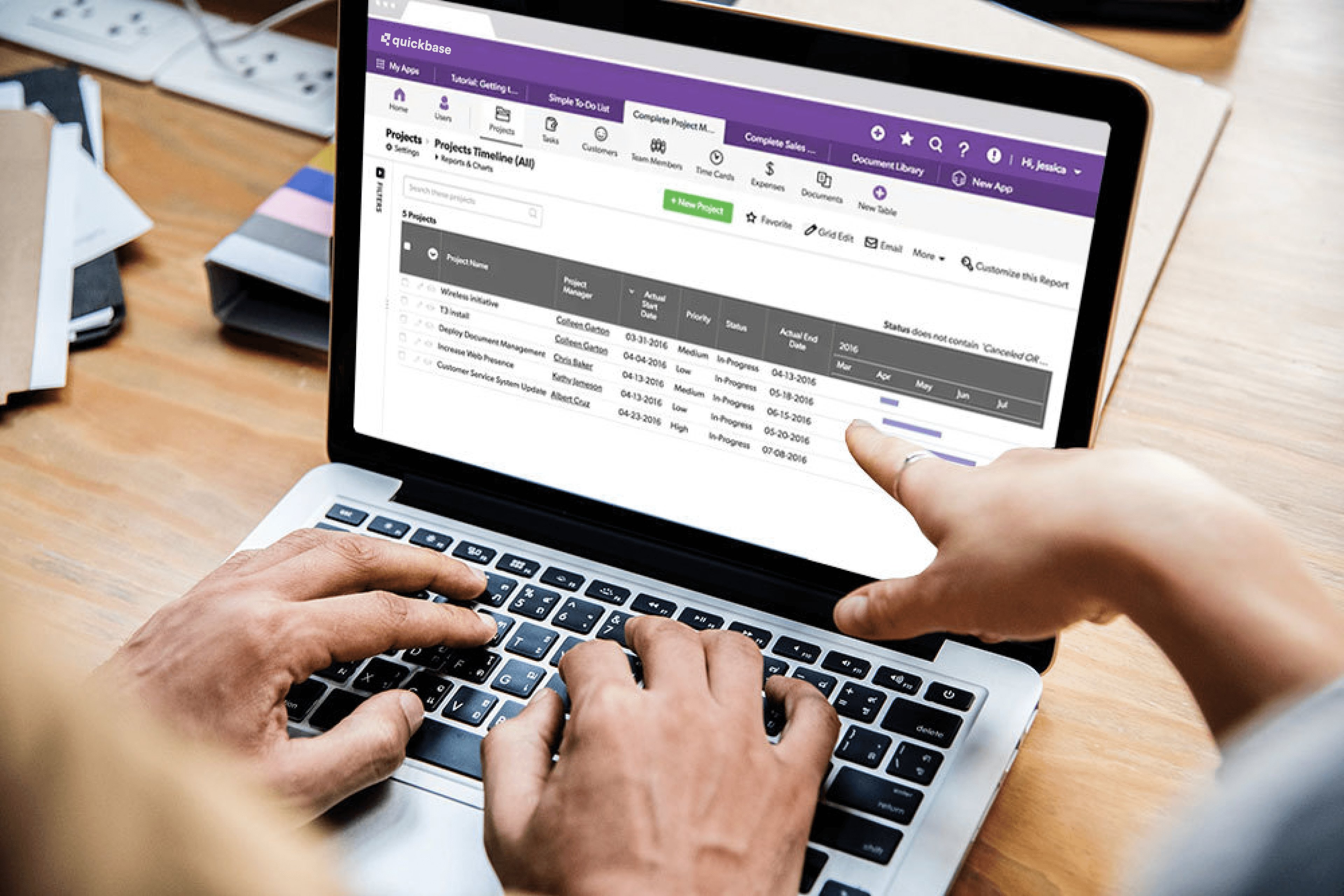 Two people discuss a Quickbase app on a laptop